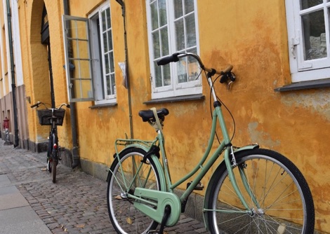 Green bicycle leaning against a yellow wall